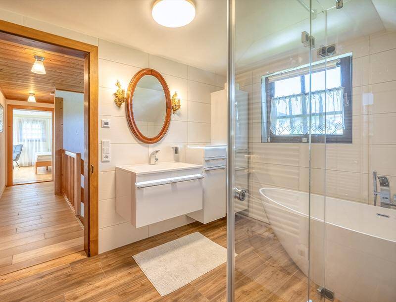 Modernes Badezimmer mit freistehender Badewanne, Glasdusche und Einzelwaschbecken mit Spiegelschrank.