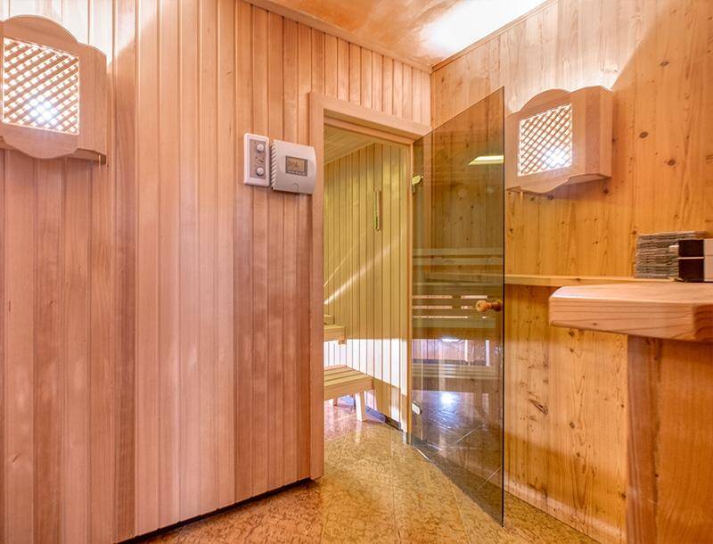 Private Holzsauna mit Glasür und Steuerungselementen, ideal für Entspannung und Wellness.