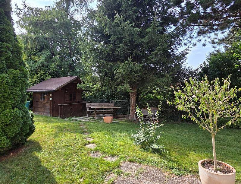 Idyllischer Gartenbereich mit Gartenhaus, Picknicktisch und altem Baumbestand.