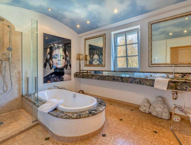 Luxuriöses Badezimmer mit Doppelwaschbecken, Badewanne, begehbarer Dusche und Marmoroberflächen.