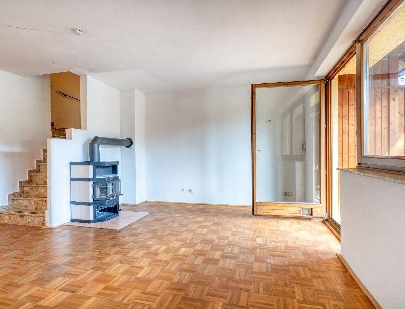 Helles Wohnzimmer mit Parkettboden, Kaminofen und Zugang zu einer Terrasse.