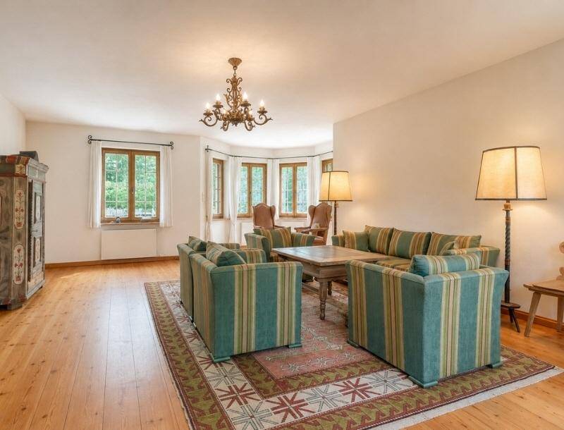Geräumiges Wohnzimmer mit Holzboden, traditionellen Möbeln und großen Fenstern.