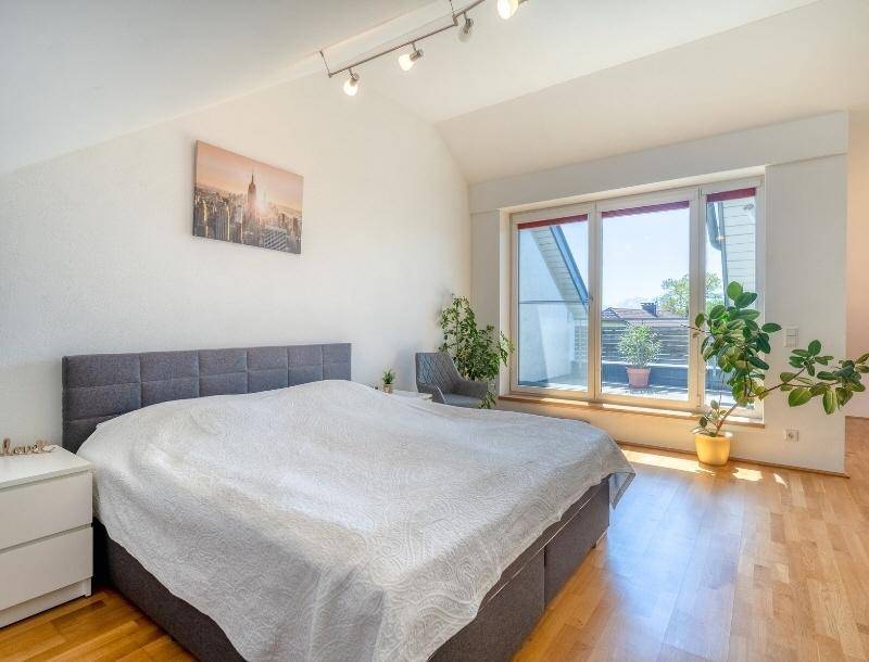 Helles Schlafzimmer mit Holzboden, großem Bett und Zugang zu einem Balkon.