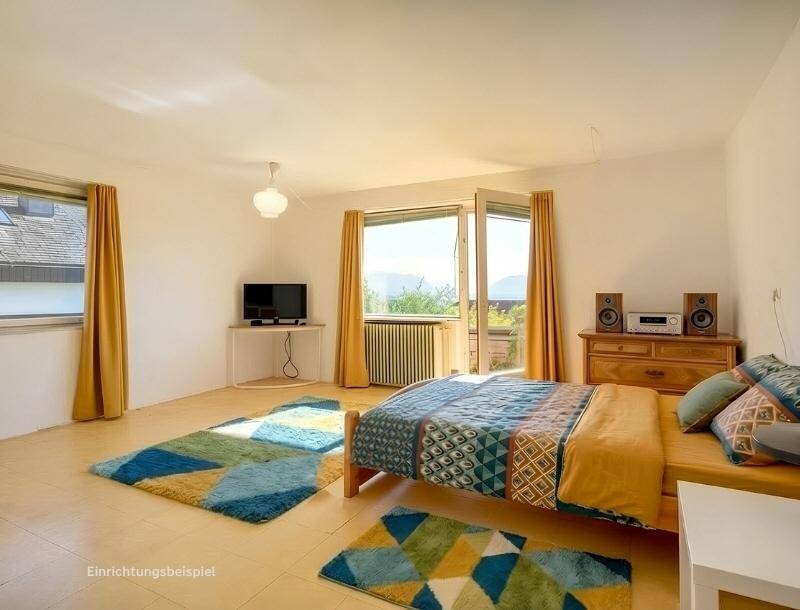Helles Schlafzimmer mit Balkonzugang, bunten Teppichen und weitem Blick in die Landschaft.