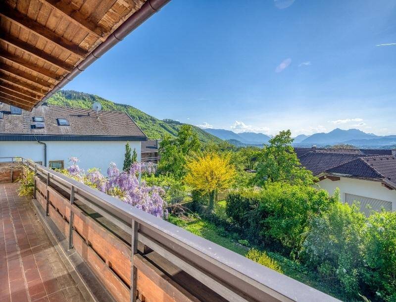 Großer Balkon mit Fliesenboden und Holzgeländer, bietet einen weiten Berg- und Landschaftsblick.