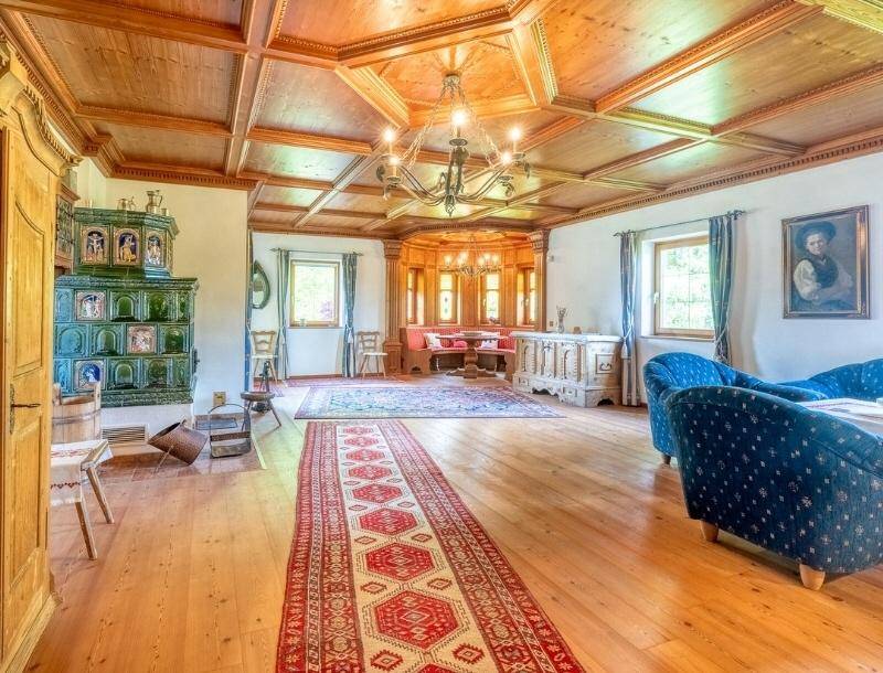 Geräumiges Wohnzimmer mit Holzkassettendecke, traditionellem Kachelofen und blauen Sofas.