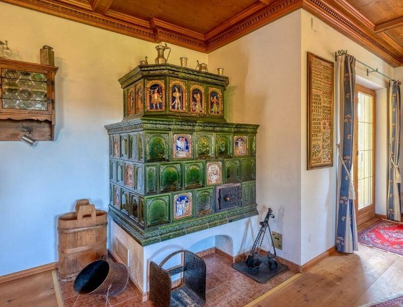 Detailansicht eines prächtigen grünen Kachelofens mit kunstvollen Verzierungen und Holzboden.
