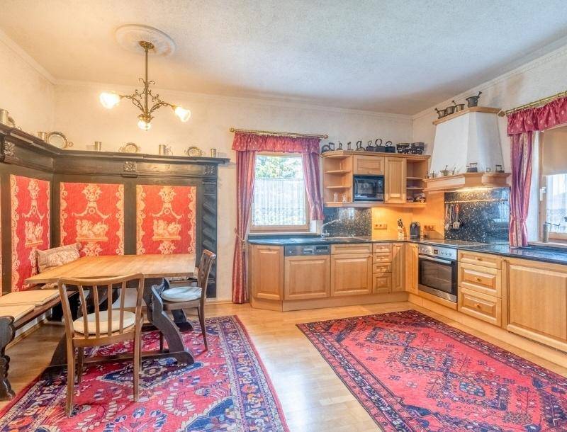 Traditionelle Küche mit Holzschränken, integriertem Essbereich und dunklen Arbeitsplatten.