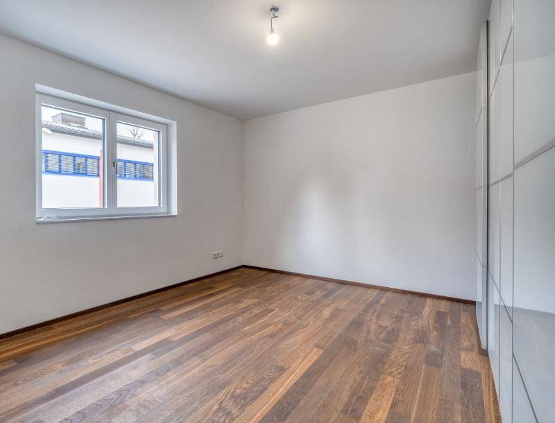 Schlafzimmer mit Holzboden und großem Fenster, bietet viel natürliches Licht.