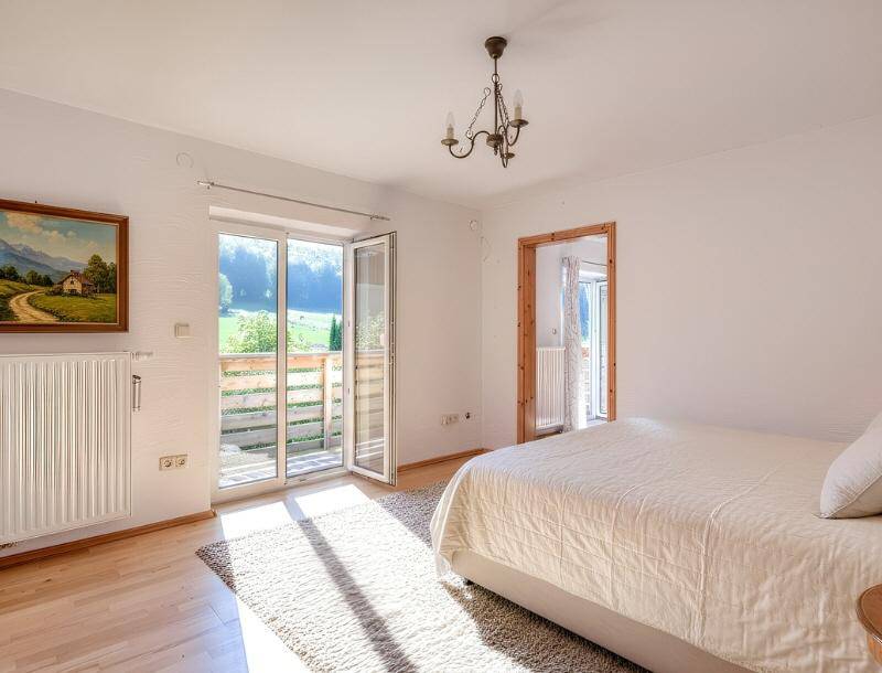 Helles Schlafzimmer mit Doppelbett und direktem Zugang zu einem sonnigen Balkon mit Weitblick.