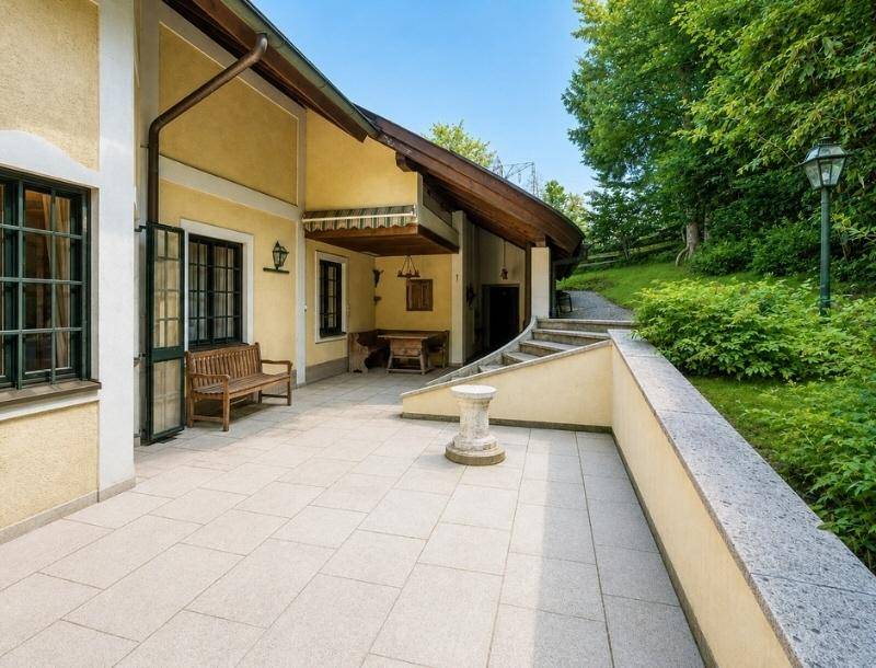 Geräumige, gepflasterte Terrasse mit Sitzbank und Zugang zum Gartenbereich des Hauses.