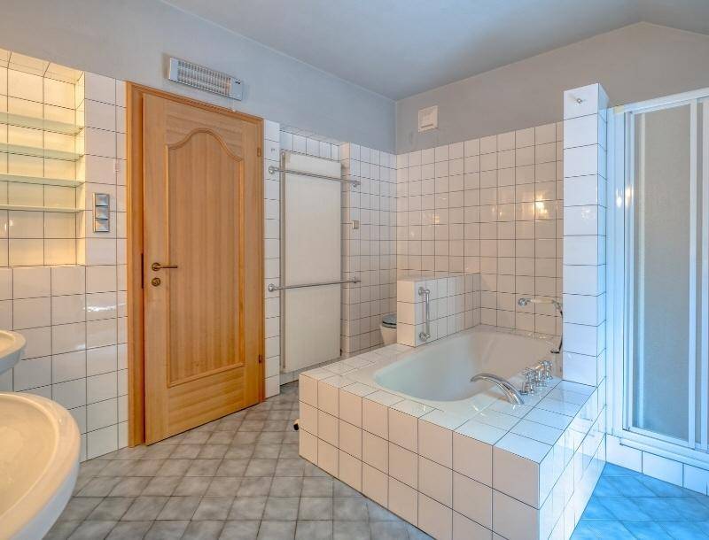 Helles Badezimmer mit weißen Fliesen, Badewanne und separater Dusche.