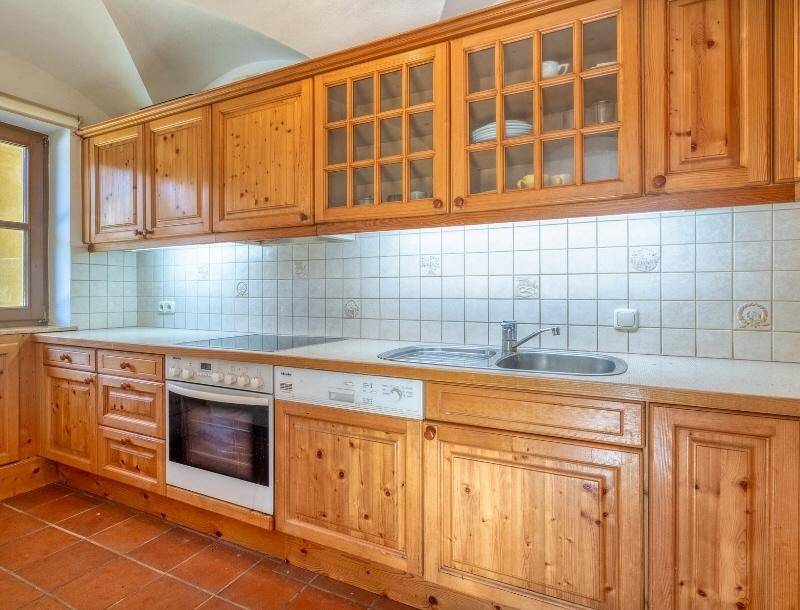 Rustikale Holzküche mit Einbaugeräten, Fliesenrückwand und Terrakottaboden.