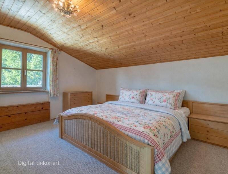 Helles Schlafzimmer mit Holzbalkendecke, Teppichboden und floraler Bettwäsche.