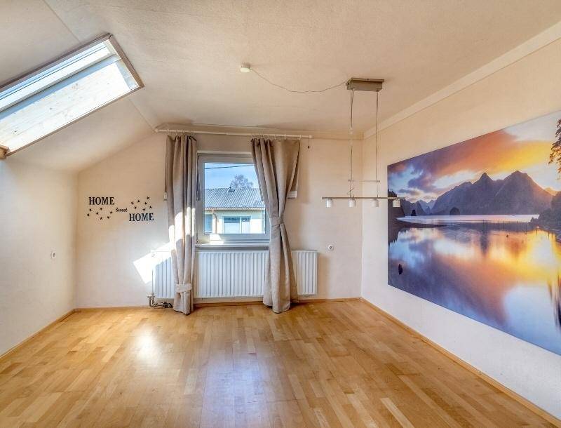 Heller Raum im Dachgeschoss mit Holzboden, Dachfenster und großem Wandbild.