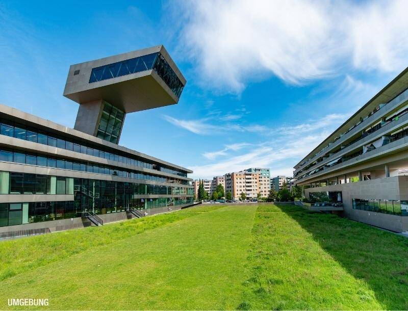 Moderne Architektur mit weitläufigen Grünflächen und einer städtischen Umgebung.