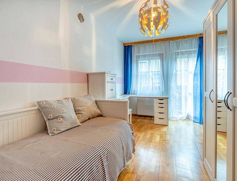 Freundliches Kinderzimmer mit Einzelbett, Schreibtisch und hellem Parkettboden.