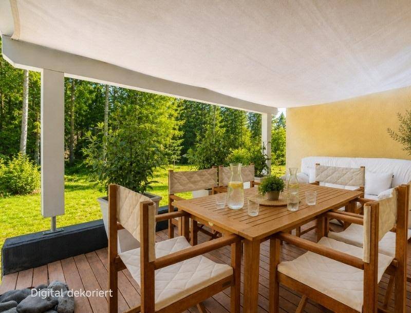 Überdachte Terrasse mit Holzboden, Esstisch und Lounge-Bereich, umgeben von viel Grün.