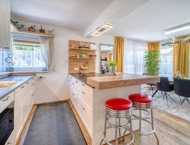 Helle Küche mit weißer Einbauküche, Holztheke und offener Verbindung zum Essbereich.