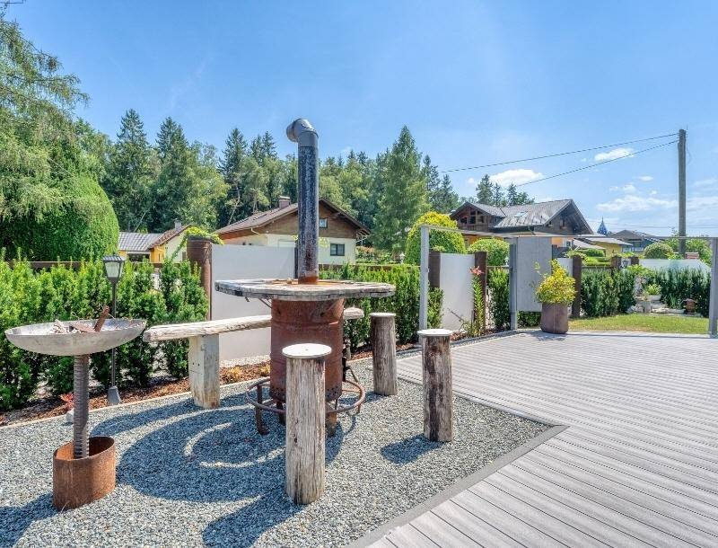 Rustikaler Außenbereich mit Feuerstelle, Kiesboden und Sitzgelegenheiten im Garten.