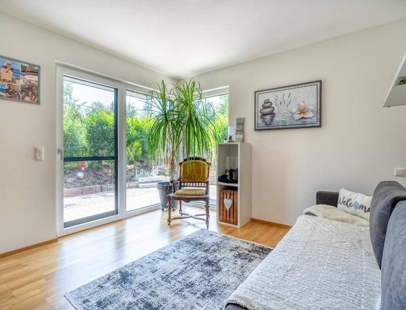 Heller Raum mit Sofa, großem Fenster und direktem Blick in den Garten.