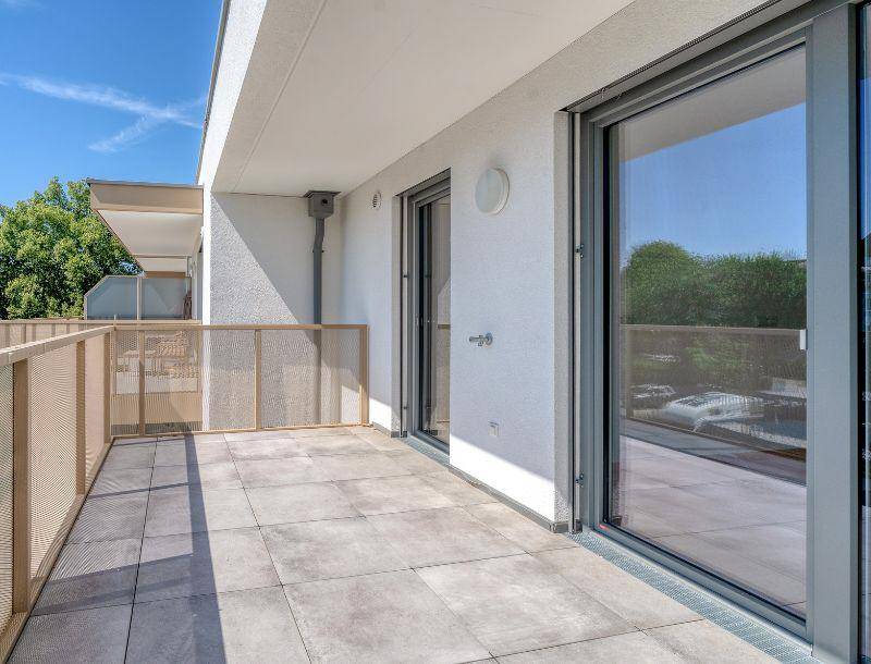 Geräumiger Balkon mit Fliesenboden und moderner Brüstung, bietet Platz für Entspannung im Freien.