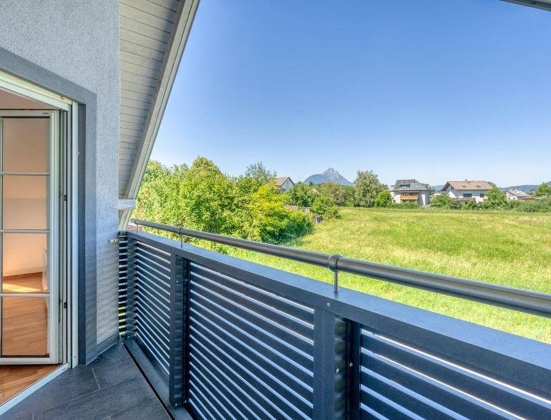 Balkon mit weitem Blick über grüne Felder und majestätische Berge in der Ferne.