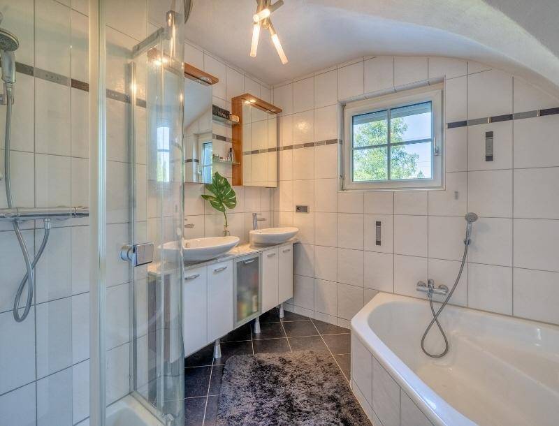 Modernes Badezimmer mit Doppelwaschbecken, Dusche, Eckbadewanne und Fenster.