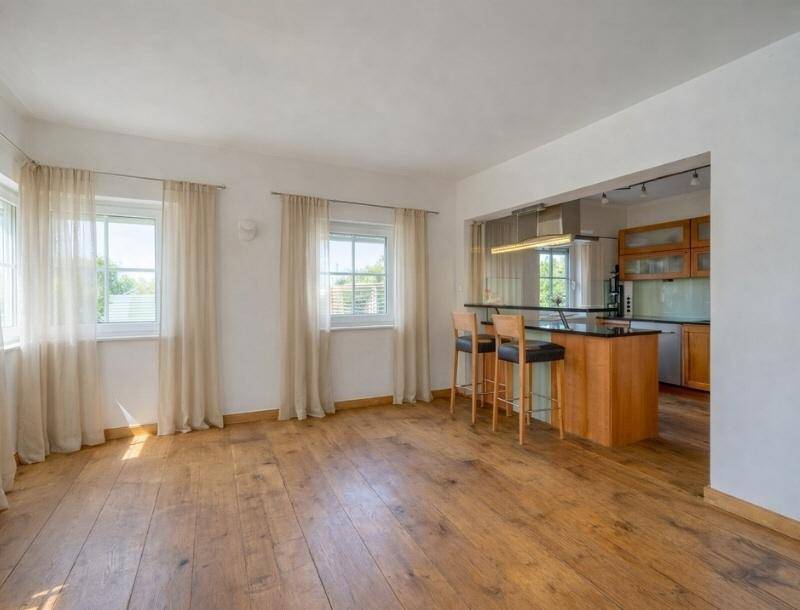 Heller Wohnbereich mit Holzdielen und einer halboffenen Küche mit Frühstücksbar.