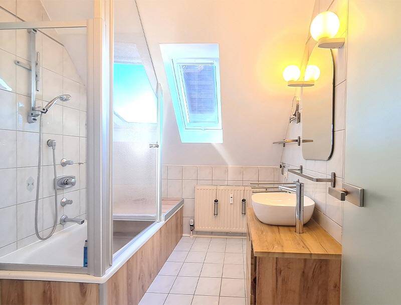 Helles Badezimmer mit Badewanne, Dusche, modernem Waschtisch und Dachfenster.