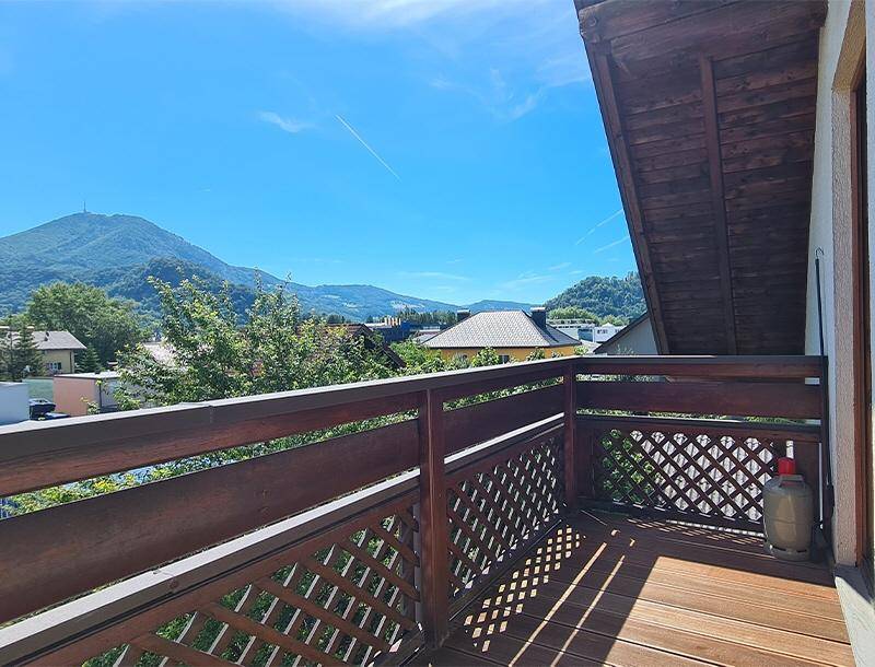 Geräumiger Holzbalkon mit Gittergeländer und weitem Blick auf die Berglandschaft.