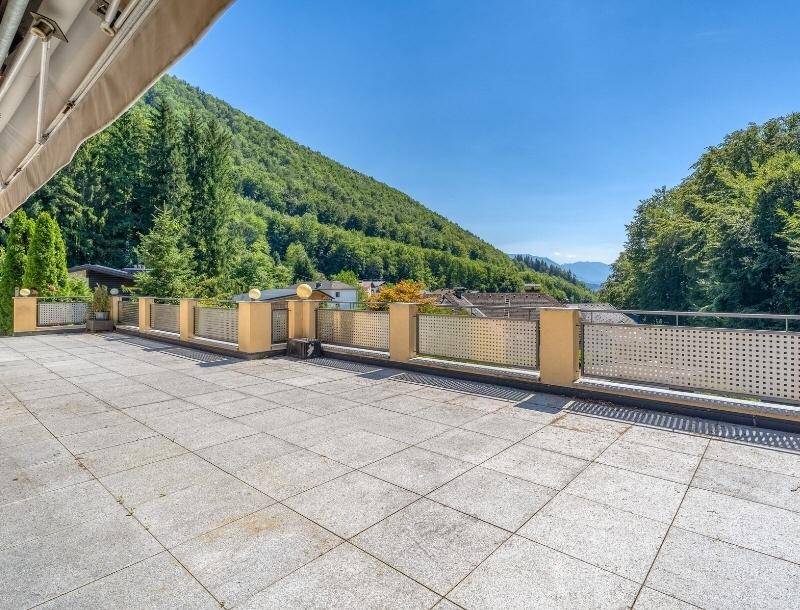 Weitläufige Terrasse mit Fliesenboden und Panoramablick auf die umliegenden grünen Berge.