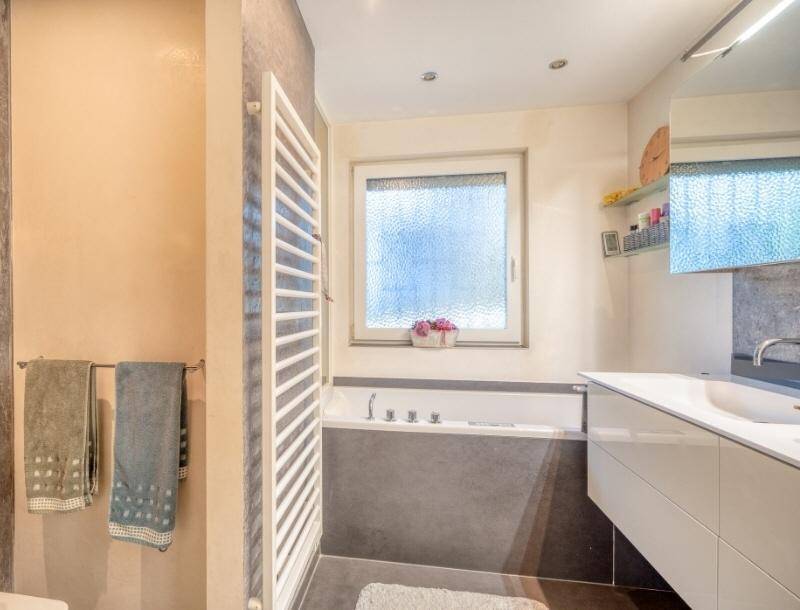 Modernes Badezimmer mit Badewanne, Einzelwaschbecken, beheiztem Handtuchhalter und Fenster für Tageslicht.