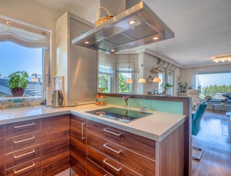 Moderne Küche mit Holzschränken, heller Arbeitsplatte und Induktionskochfeld, offen zum Wohnbereich.