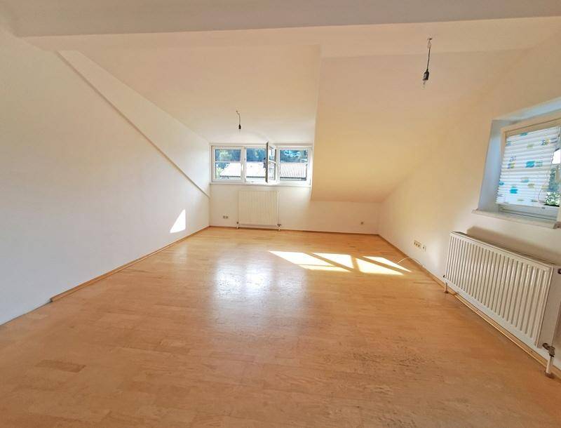 Heller Raum im Dachgeschoss mit Holzboden, Dachschrägen und Fenstern, bereit zur individuellen Gestaltung.