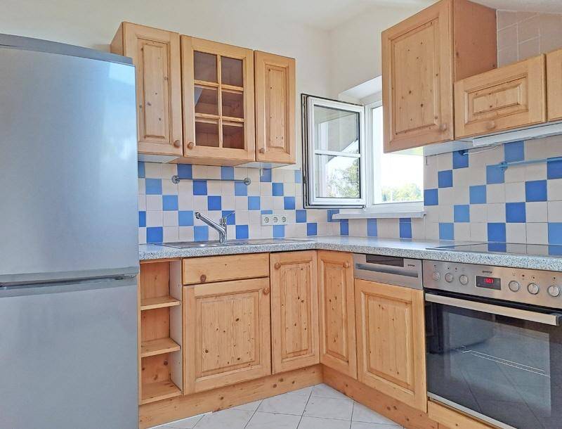 Traditionelle Küche mit hellen Holzschränken, blau-weiß gefliestem Spritzschutz und modernen Geräten.