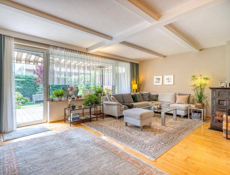 Helles Wohnzimmer mit Holzboden, gemütlicher Sitzecke und Zugang zur Terrasse mit Gartenblick.