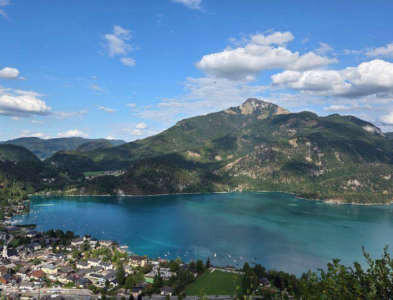 Panoramablick auf einen malerischen See, eine charmante Stadt und die umliegende Berglandschaft.
