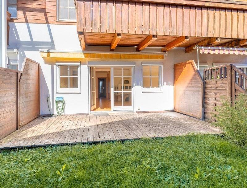 Geräumige Holzterrasse mit Rasenfläche und direktem Zugang zum Haus.