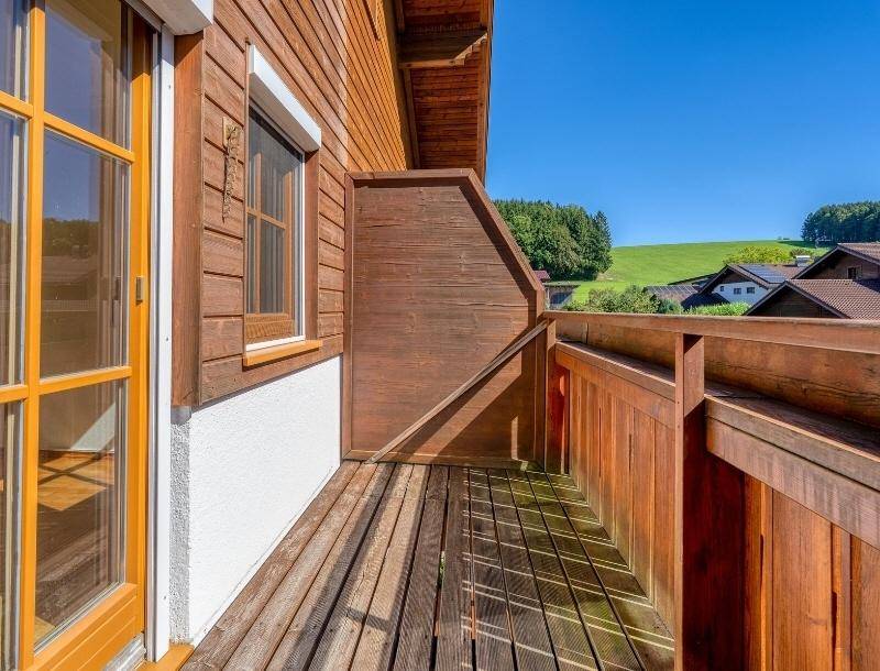 Holzbalkon mit weitem Blick über grüne Hügel und die umliegende Landschaft.