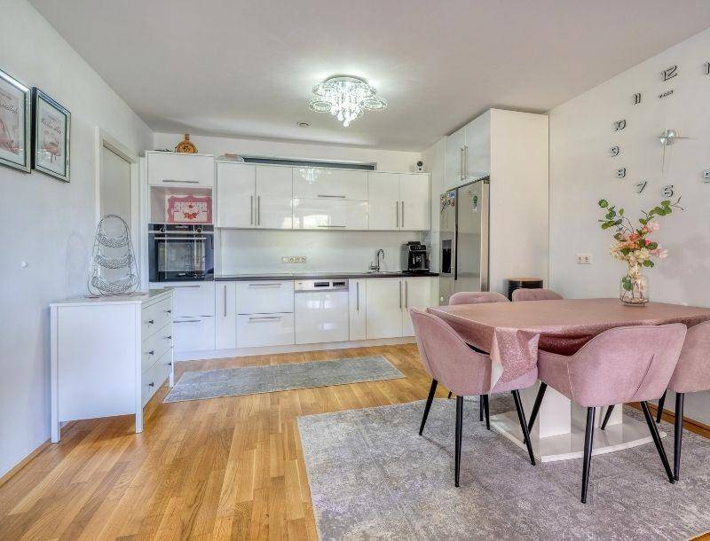 Moderne Wohnküche mit weißen Hochglanzschränken, Holzboden und Essbereich.