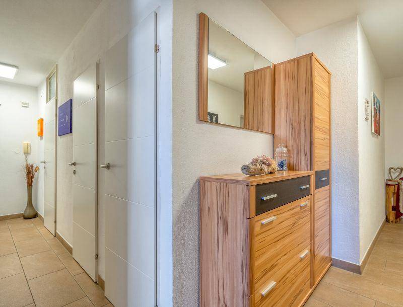 Heller Flur mit praktischem Schuhschrank, Spiegel und Fliesenboden.