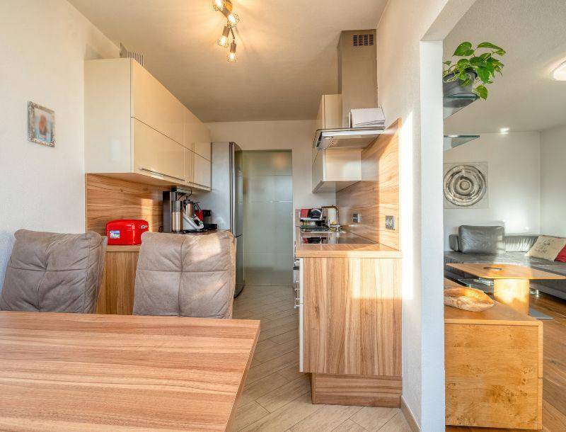 Moderne Küche mit Holzfronten, integrierten Geräten und Essbereich.