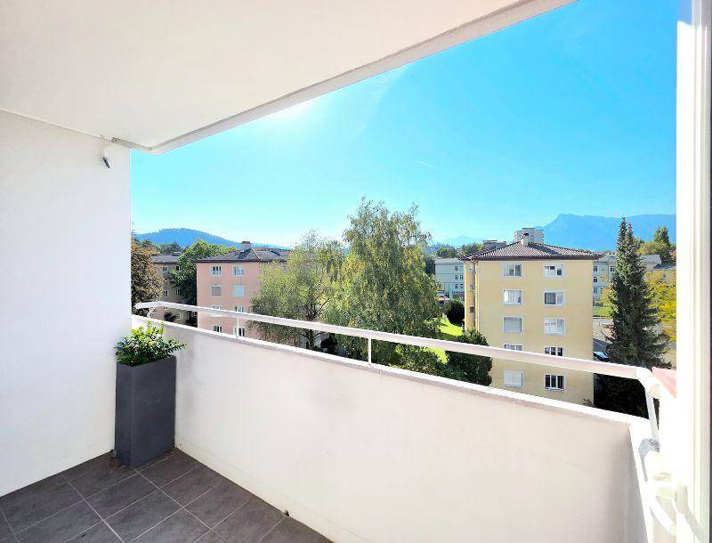 Sonniger Balkon mit Fliesenboden und weitem Blick über die Umgebung und Berge.