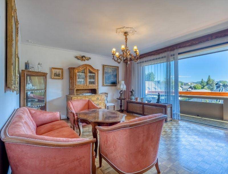 Helles Wohnzimmer mit antiken Möbeln, Parkettboden und Zugang zu einem Balkon mit Weitblick.