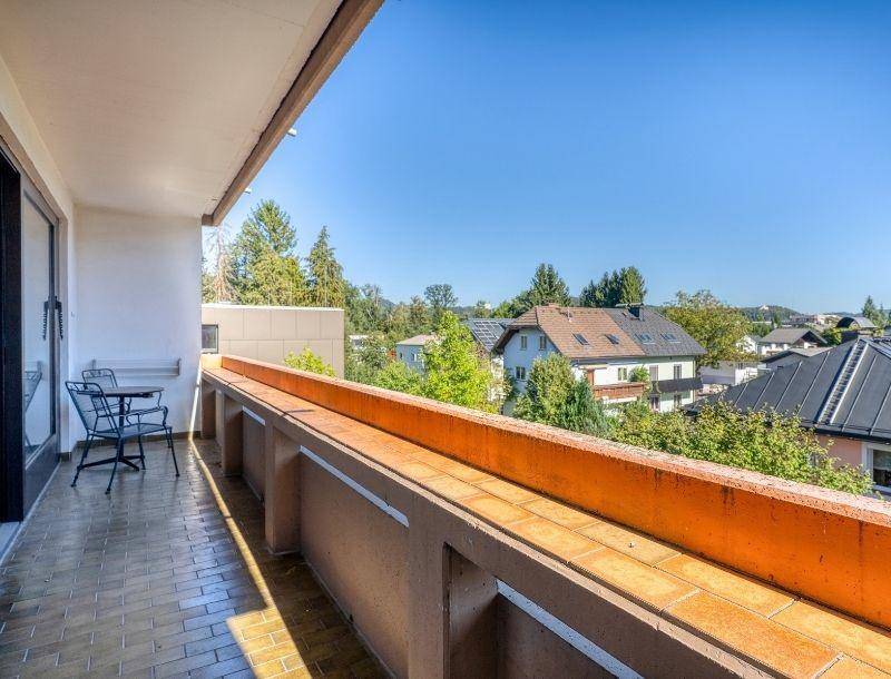 Geräumiger Balkon mit Fliesenboden und einem weiten Blick über die grüne Umgebung.