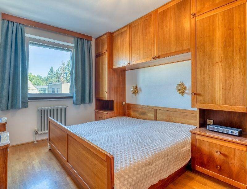 Schlafzimmer mit maßgefertigten Holzschränken, Doppelbett und Parkettboden.