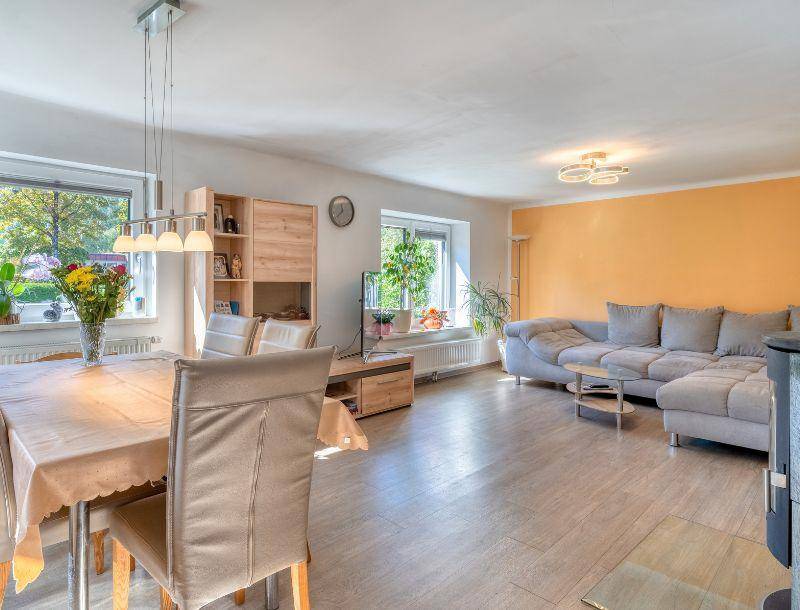 Heller Wohn-Essbereich mit gemütlichem Sofa, Esstisch und einem Kaminofen für behagliche Stunden.