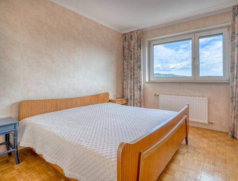 Schlafzimmer mit Doppelbett, Parkettboden und Fenster, das einen weiten Blick bietet.