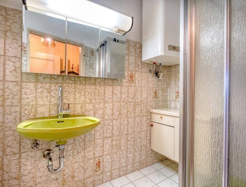 Badezimmer mit auffälligem grünem Waschbecken, Duschkabine und Wandfliesen im Vintage-Stil.
